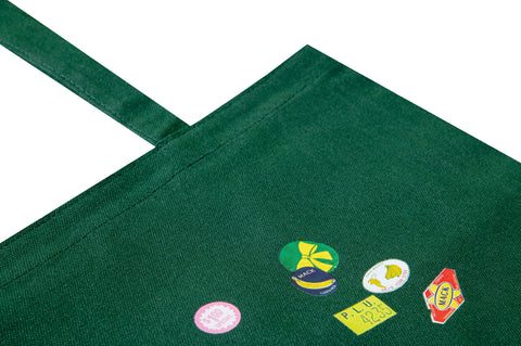Green tote bag with vibrant fruit stickers by MACK, showcasing a casual, reusable accessory with colorful fruit designs.